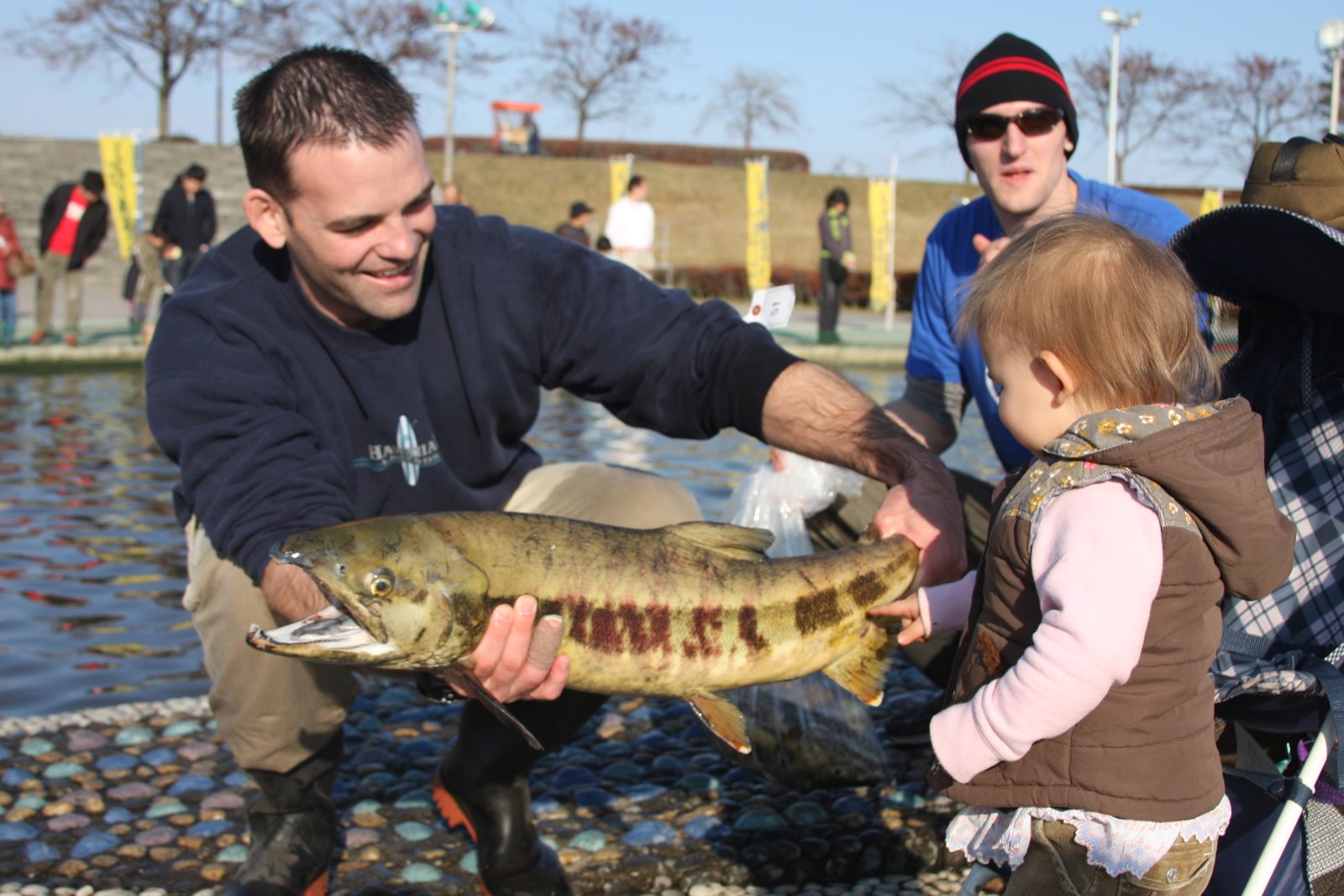 Picture of man holding a salmon in front of a little girl
